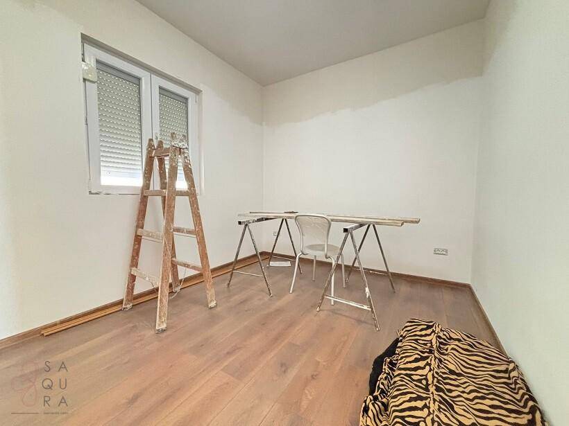 Unmöblierter Raum mit Holzboden und Fenster, der sich in Renovierung befindet, mit einer Leiter.