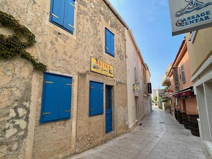 Malerische Gasse mit alten Gebäuden, blauen Fensterläden und einem kleinen Geschäft.