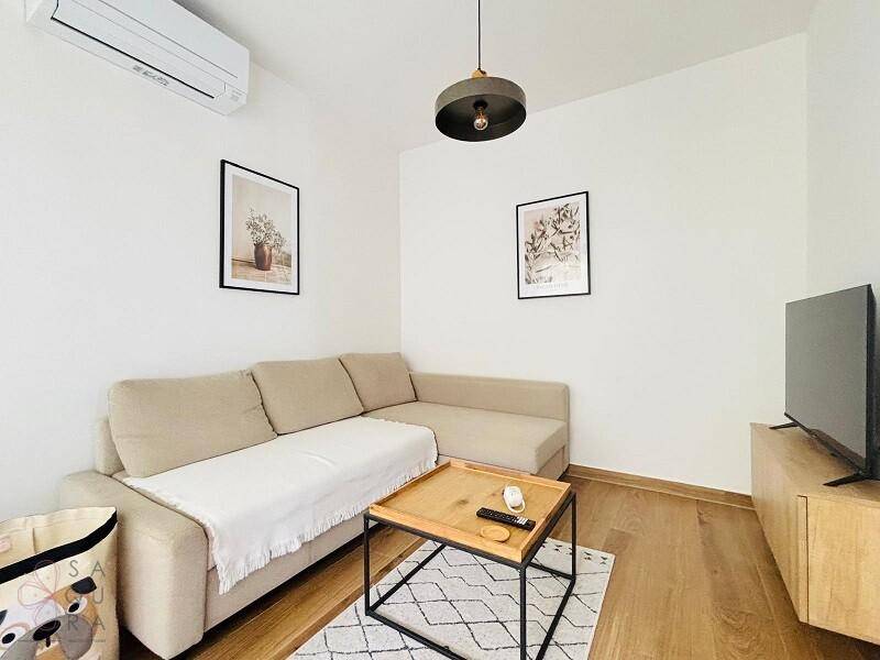 Gemütliches Wohnzimmer mit beigem Sofa, modernem Couchtisch und Klimaanlage für Komfort.
