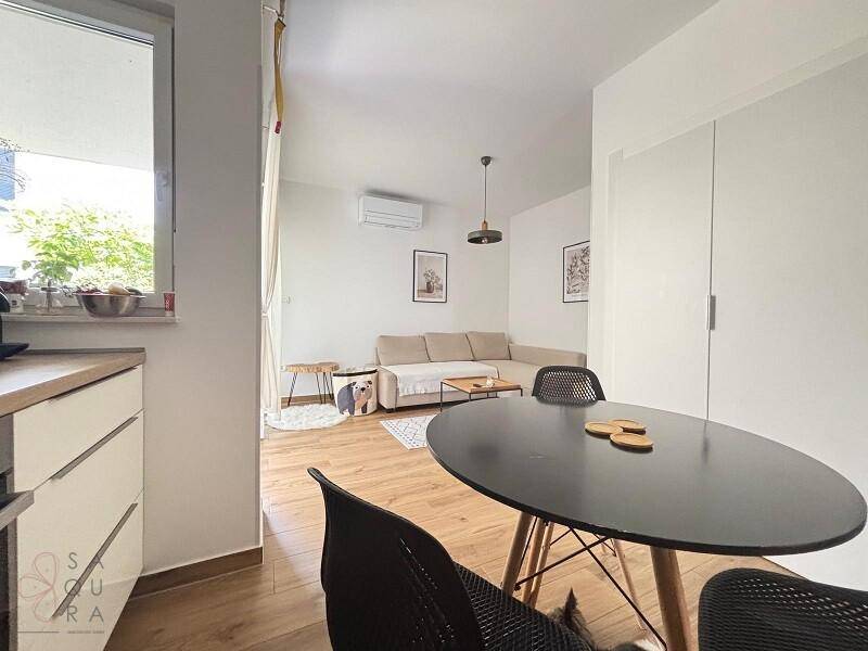 Moderner Wohn-Essbereich mit dunklem Esstisch und hellem Sofa, ausgestattet mit Klimaanlage.