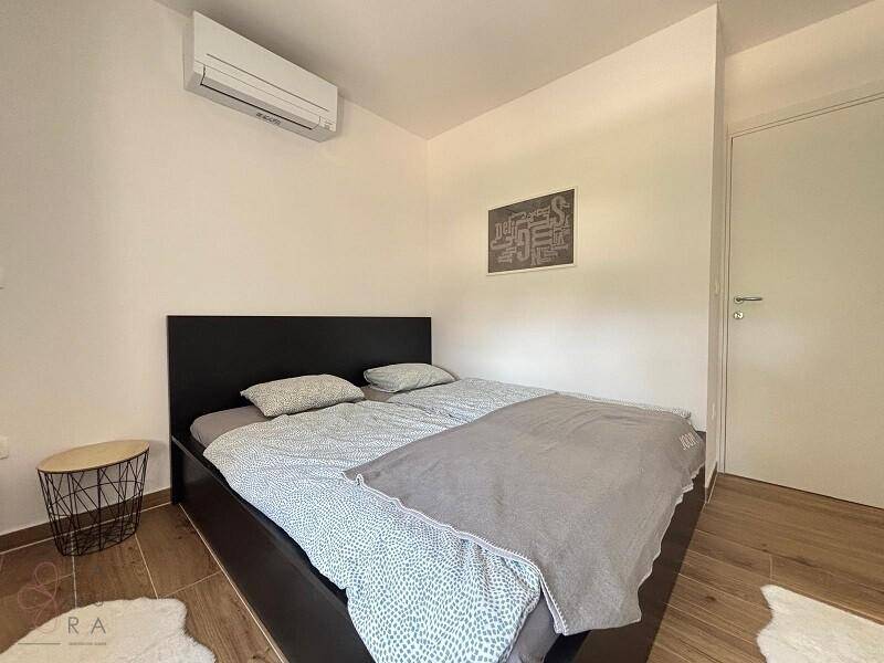 Schlafzimmer mit Doppelbett, Nachttisch und Klimaanlage für angenehme Raumtemperatur.