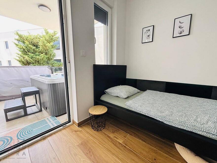 Schlafzimmer mit Einzelbett und direktem Zugang zu einer Terrasse mit Whirlpool.