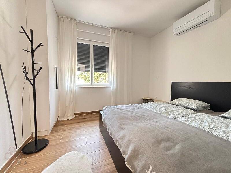Schlafzimmer mit Doppelbett, Fenster mit Rollläden und Klimaanlage für Komfort.