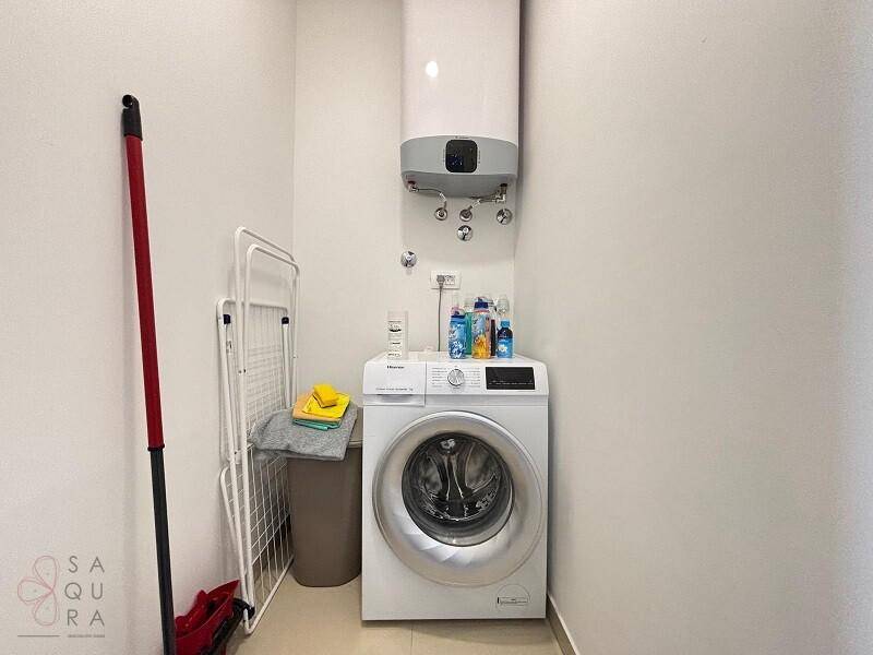 Funktionaler Hauswirtschaftsraum mit Waschmaschine und Warmwasserboiler, praktisch eingerichtet.