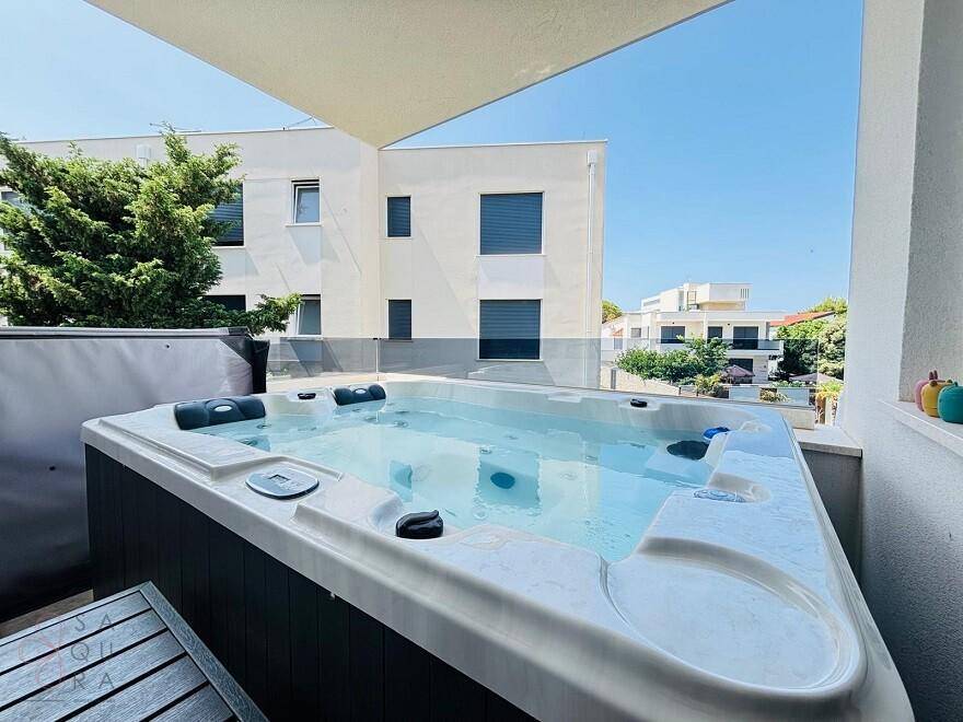 Geräumige Terrasse mit großem Whirlpool und Blick auf die umliegenden modernen Gebäude.