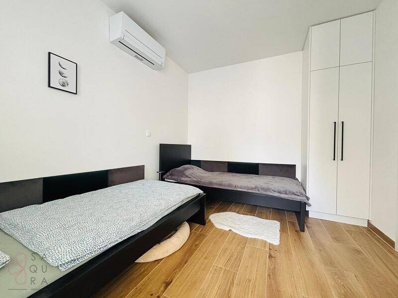 Schlafzimmer mit zwei Einzelbetten, weißem Kleiderschrank und Klimaanlage für angenehme Nächte.