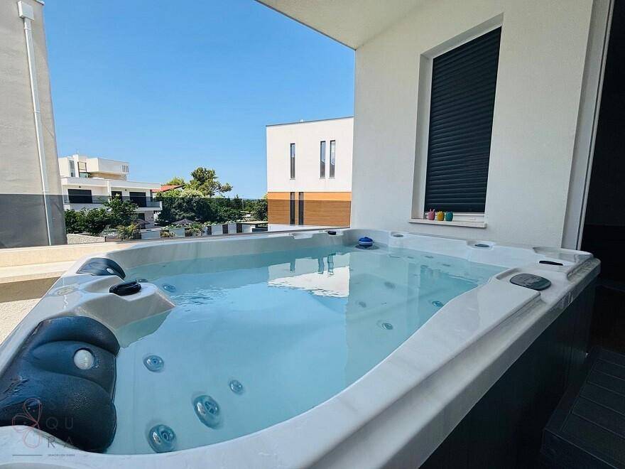 Sonnige Terrasse mit großem Whirlpool, ideal zum Entspannen unter freiem Himmel.