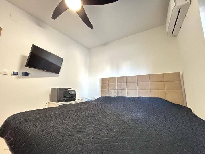 Modernes Schlafzimmer mit großem Bett, Wandfernseher und Klimaanlage.