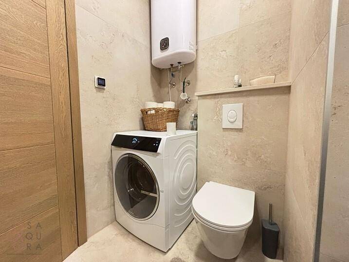 Praktischer Waschraum mit Toilette, Waschmaschine und Warmwasserbereiter.