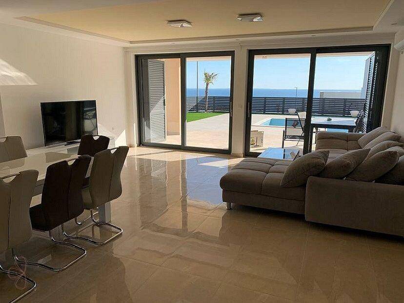 Helles Wohn-Esszimmer mit Meerblick, großen Glasschiebetüren und Zugang zur Poolterrasse.
