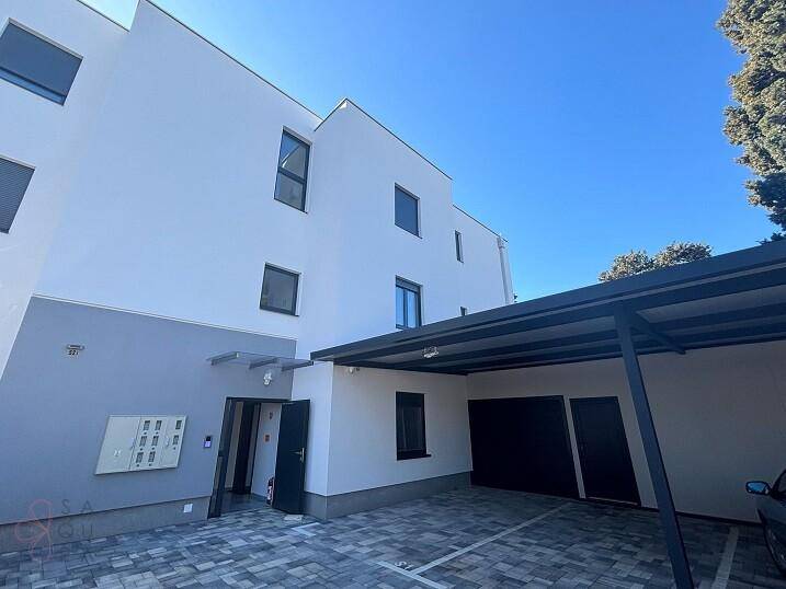 Moderne Wohnanlage mit überdachten Parkplätzen und Garagen im Freien.
