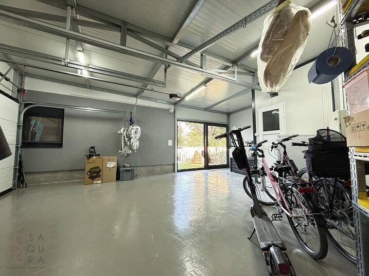 Große Garage mit viel Stauraum, Fahrrädern und Fenster zum Gartenbereich.
