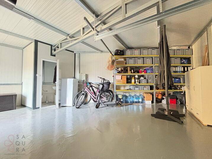 Geräumige Garage mit Lagerregalen, Fahrrädern und Zugang zu einem weiteren Raum.