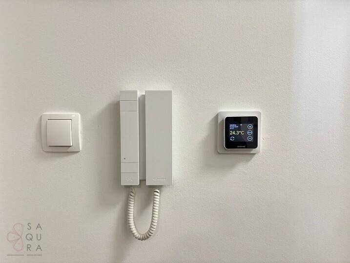 Wandmontierte Gegensprechanlage und modernes Thermostat für Komfort und Sicherheit.
