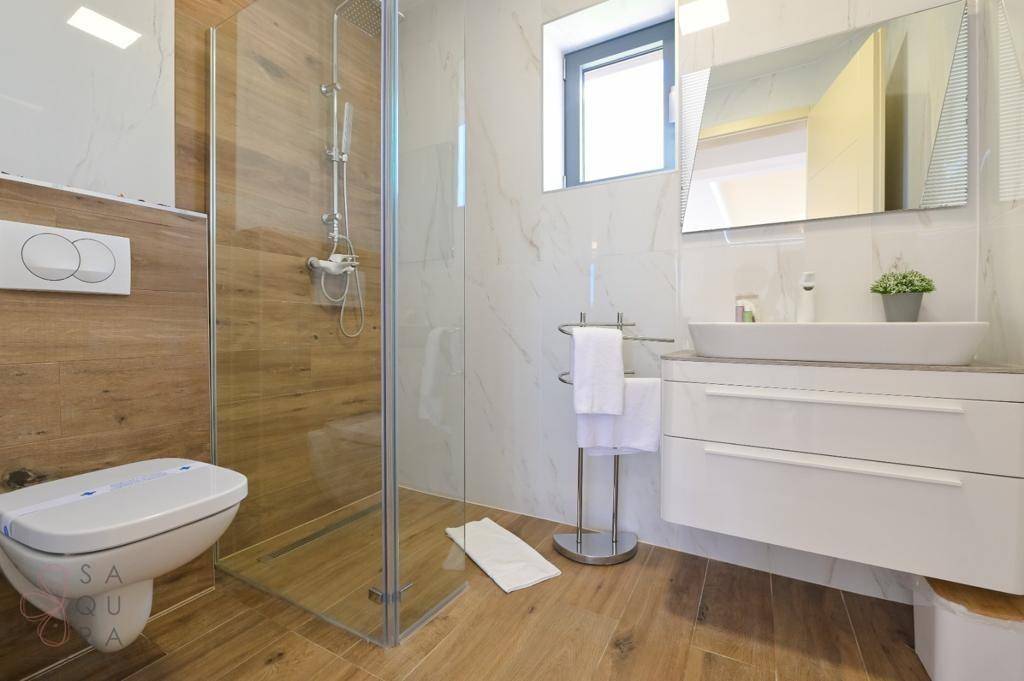 Modernes Badezimmer mit begehbarer Dusche, Wand-WC und stilvollen Holz- und Marmorfliesen.
