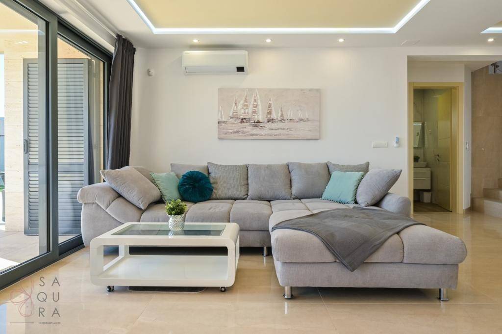 Gemütliches Wohnzimmer mit großem Ecksofa, Klimaanlage und direktem Zugang zur Terrasse.