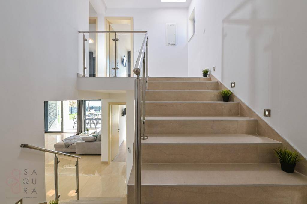Moderne Treppe mit Glasgeländer und Fliesenstufen, die die Etagen stilvoll verbindet.