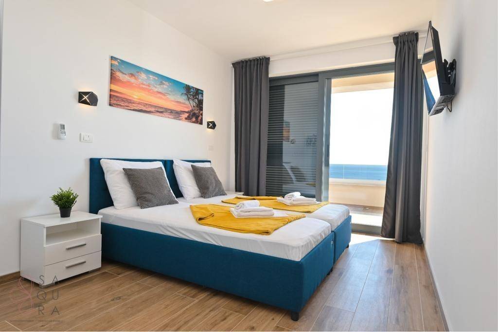 Helles Schlafzimmer mit zwei Einzelbetten und Balkonzugang, der einen weiten Meerblick bietet.