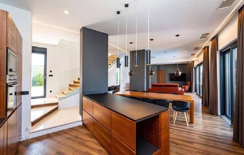 Offener Wohn- und Essbereich mit moderner Küche und eleganter Treppe, die die Etagen verbindet.