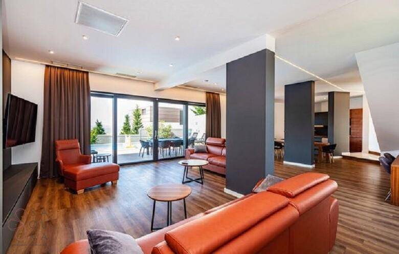 Geräumiges Wohnzimmer mit bequemen Sofas und großen Fenstern, die viel Tageslicht hereinlassen.
