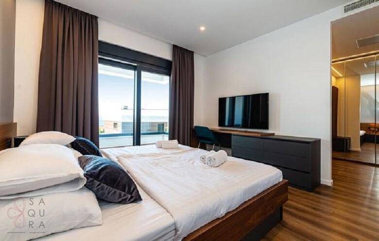 Helles Schlafzimmer mit Holzboden, Spiegelfront und Zugang zu einem privaten Balkon.