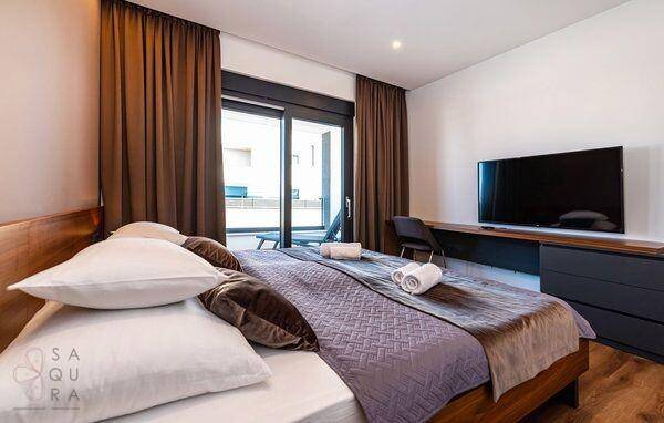 Komfortables Schlafzimmer mit großem Bett, Fernseher und direktem Zugang zum Balkon.