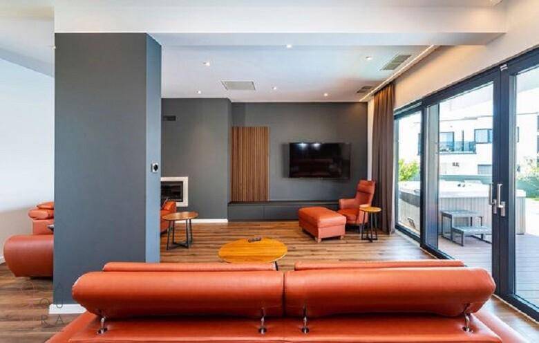 Modernes Wohnzimmer mit Fernseher, Kamin und großen Schiebetüren zur Terrasse mit Whirlpool.