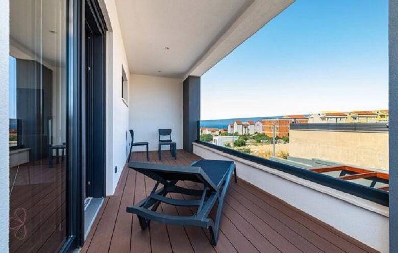 Sonniger Balkon mit Liegestuhl und Meerblick, ideal zum Entspannen im Freien.