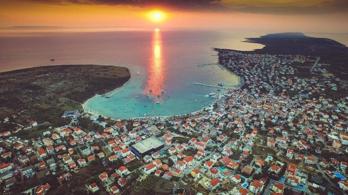 Malerische Luftaufnahme einer Küstenstadt bei Sonnenuntergang mit vielen Häusern und einem Hafen.