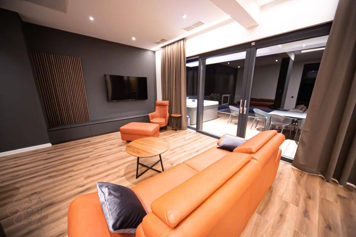 Gemütliches Wohnzimmer mit Fernseher und Zugang zur Außenterrasse, perfekt für Entspannung.