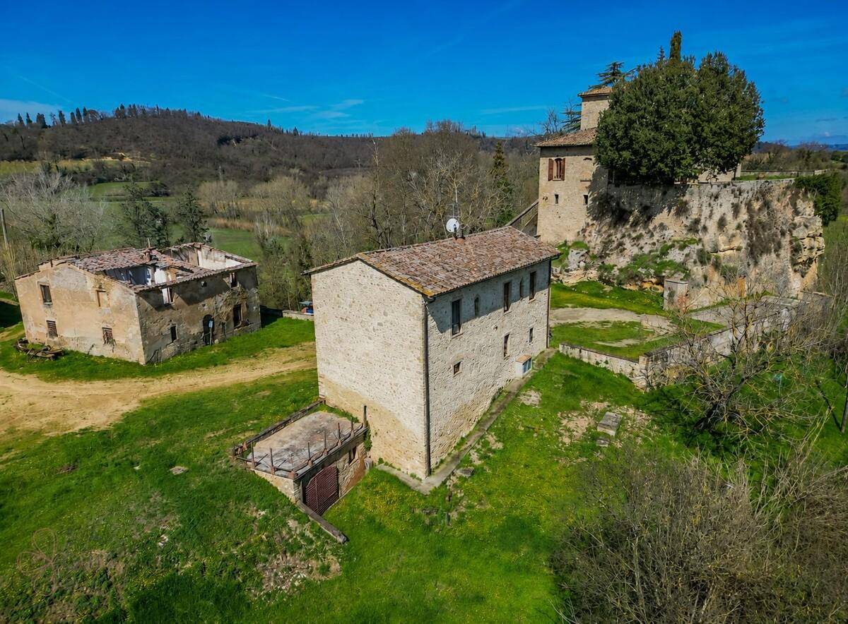 Luftaufnahme eines Anwesens mit mehreren historischen Gebäuden und weitläufiger grüner Landschaft.