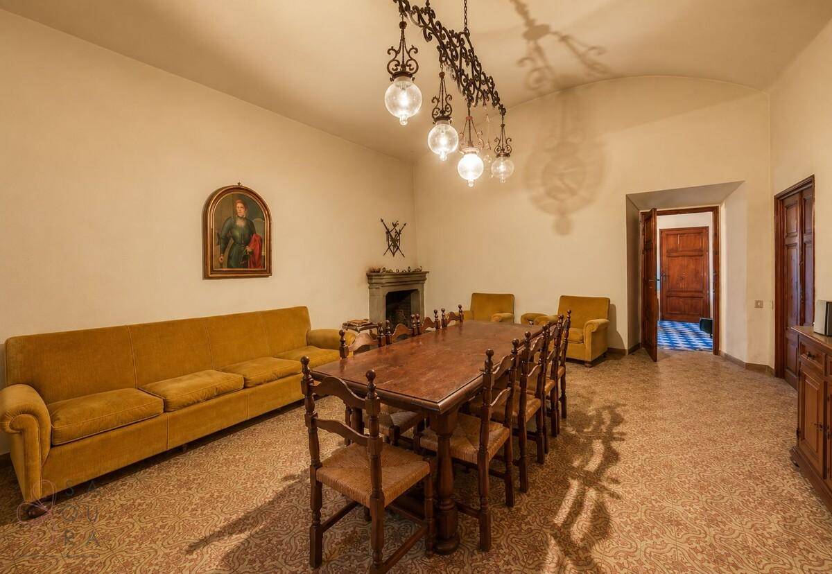 Geräumiger Essbereich mit rustikalem Holztisch, bequemen Sofas und einem dekorativen Kamin.
