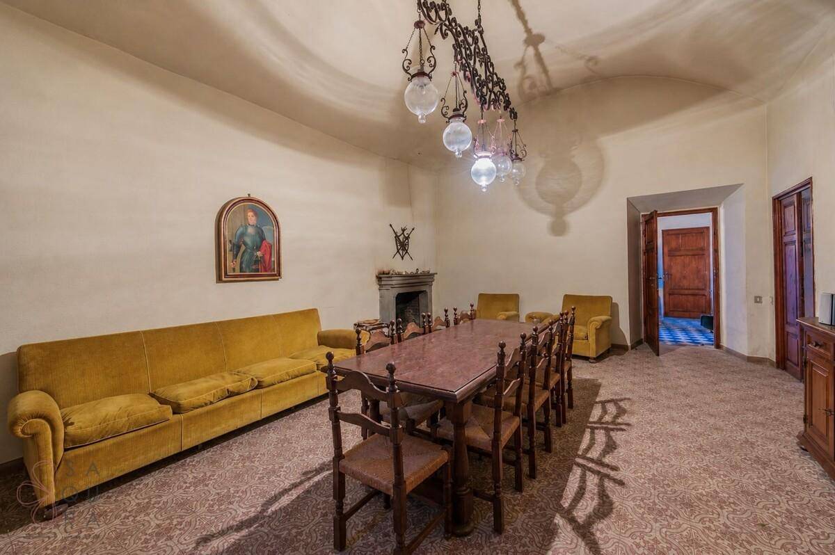 Traditioneller Essbereich mit großem Holztisch, gelben Sofas und einem Kamin.