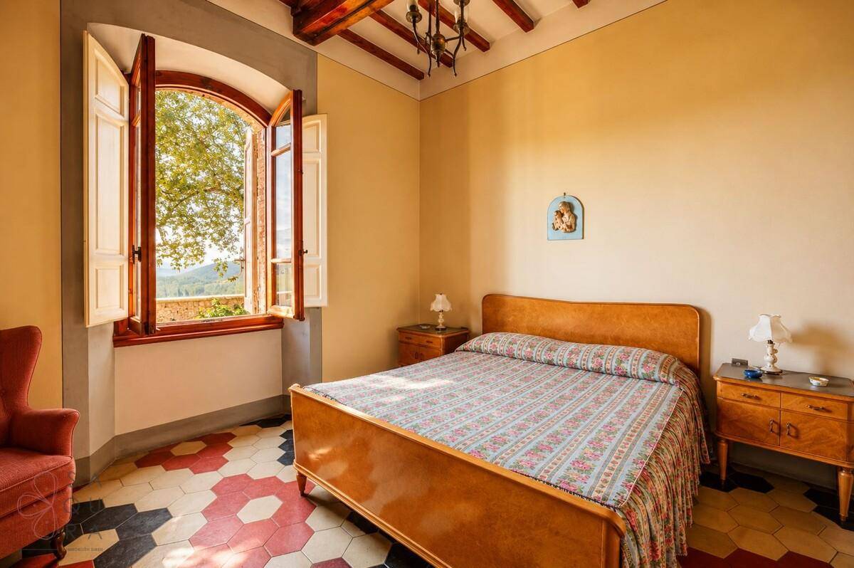 Helles Schlafzimmer mit Holzbalkendecke, traditionellen Möbeln und Blick ins Grüne.
