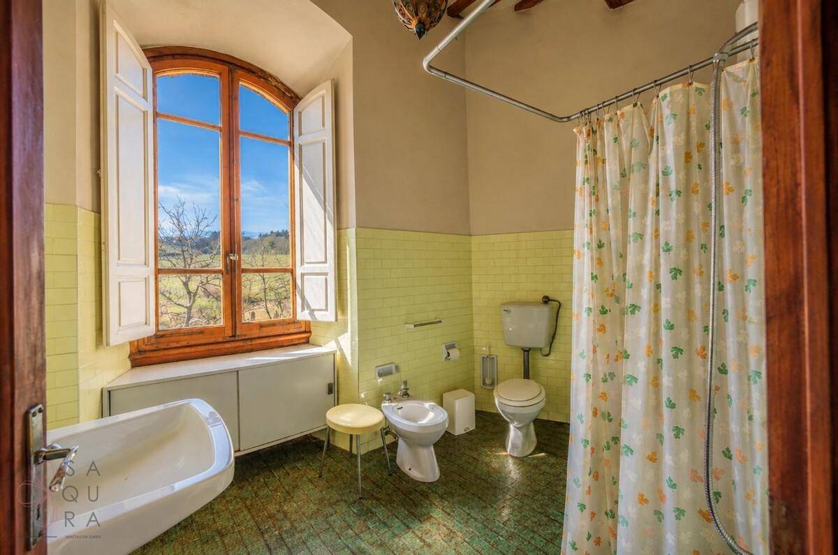 Helles Badezimmer mit gelben Fliesen, Badewanne, Bidet und weitem Blick ins Grüne.