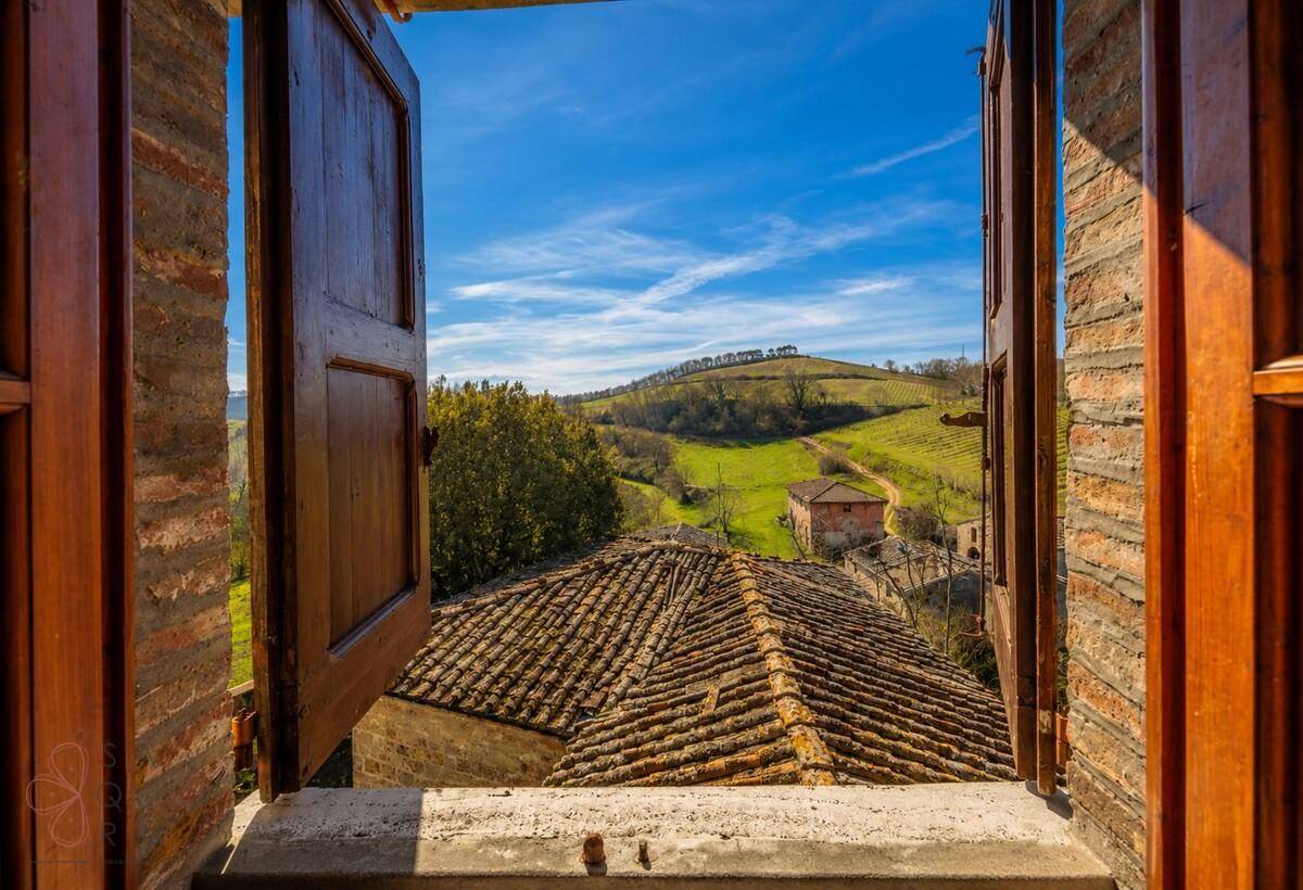 Malerischer Ausblick aus einem Fenster auf die toskanische Landschaft mit Ziegeldächern.