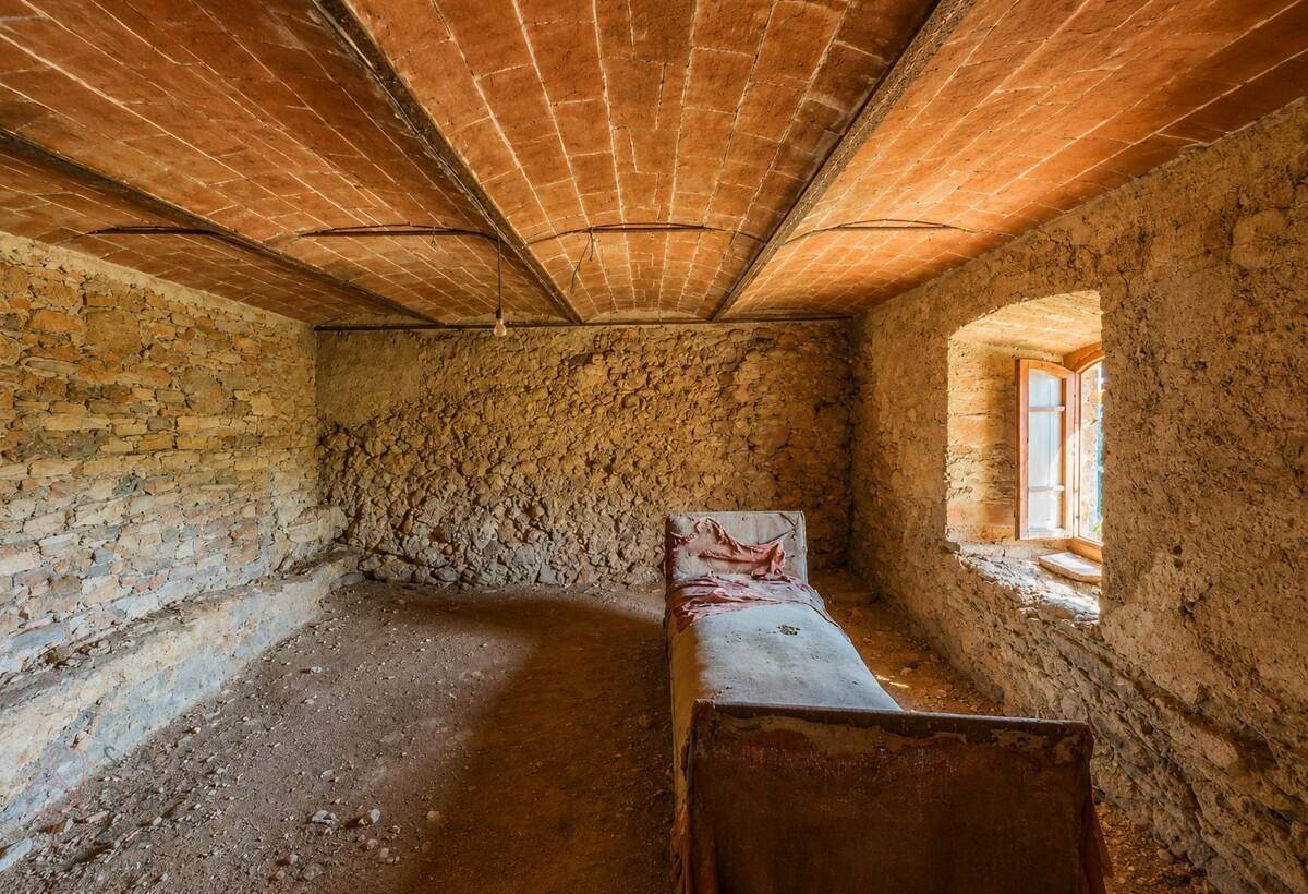 Rustikales Schlafzimmer in einem Rohbau mit Steinwänden, Ziegeldecke und kleinem Fenster.
