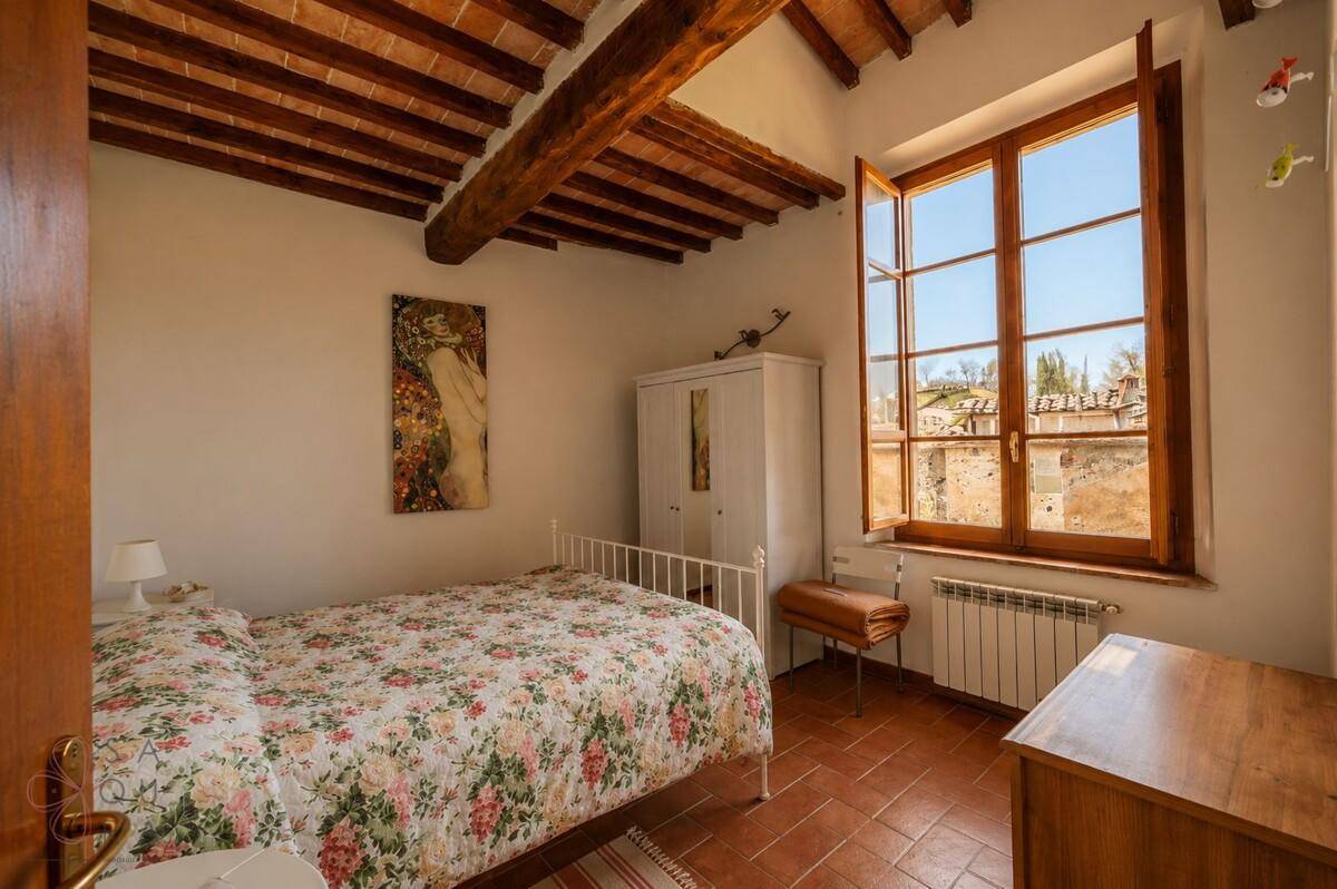 Einfaches Schlafzimmer mit Terrakotta-Fliesen, weißem Kleiderschrank und Fenster mit Ausblick.