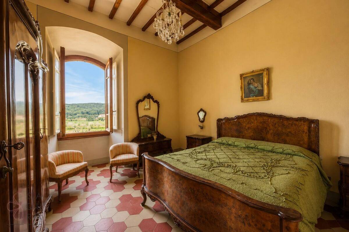 Geräumiges Schlafzimmer mit antiken Möbeln, Holzbalkendecke und weitem Blick in die Natur.