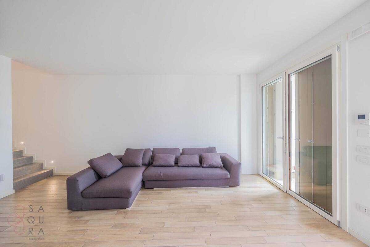 Geräumiges Wohnzimmer mit modernem Ecksofa und hellem Holzfußboden.