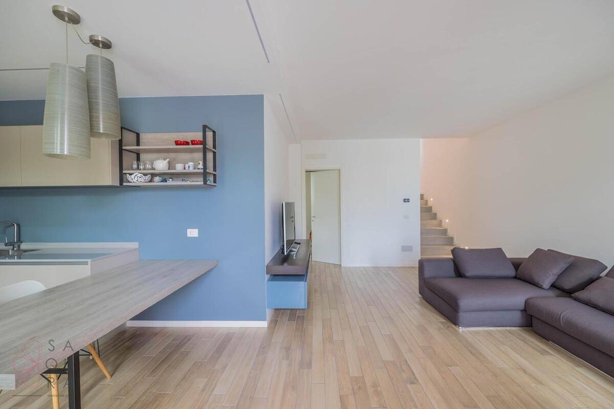 Heller offener Wohn- und Essbereich mit moderner Küche und gemütlichem Sofa.