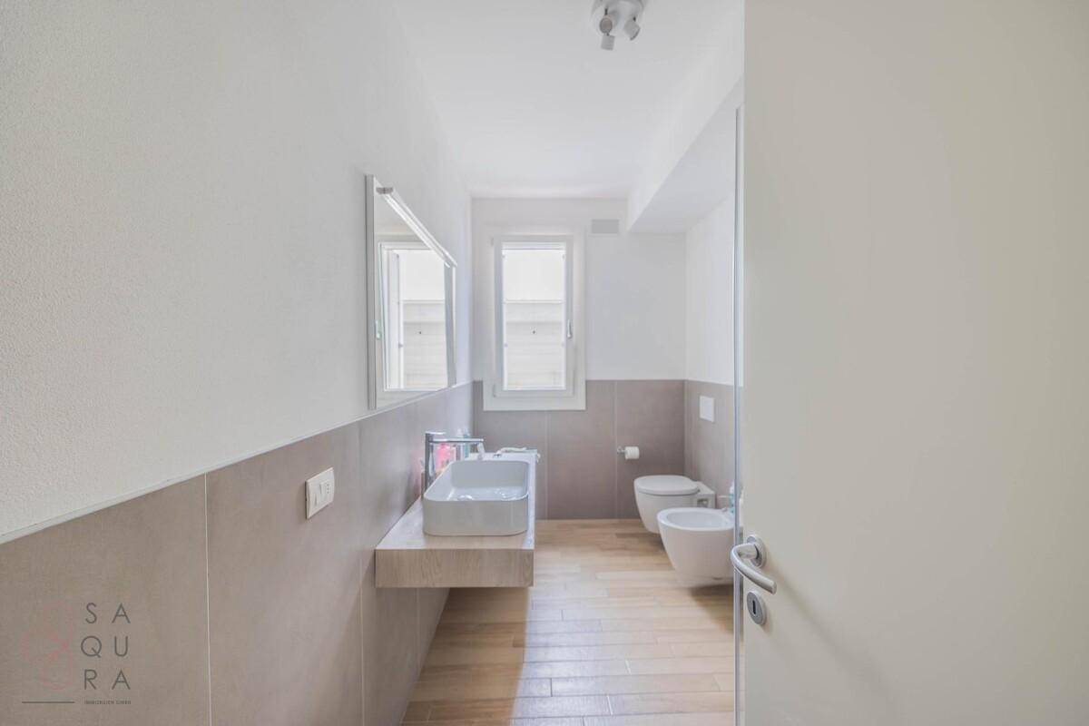 Helles Badezimmer mit modernem Waschtisch, Toilette, Bidet und Fenster.