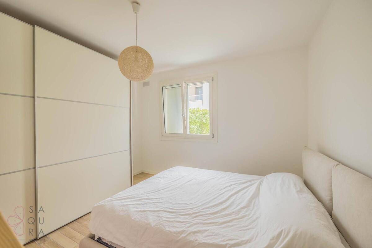 Schlafzimmer mit Doppelbett, großem Einbauschrank und Fenster mit Blick ins Grüne.