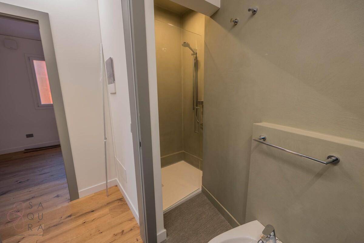 Modernes Badezimmer mit begehbarer Dusche, beigefarbenen Fliesen und minimalistischem Design.