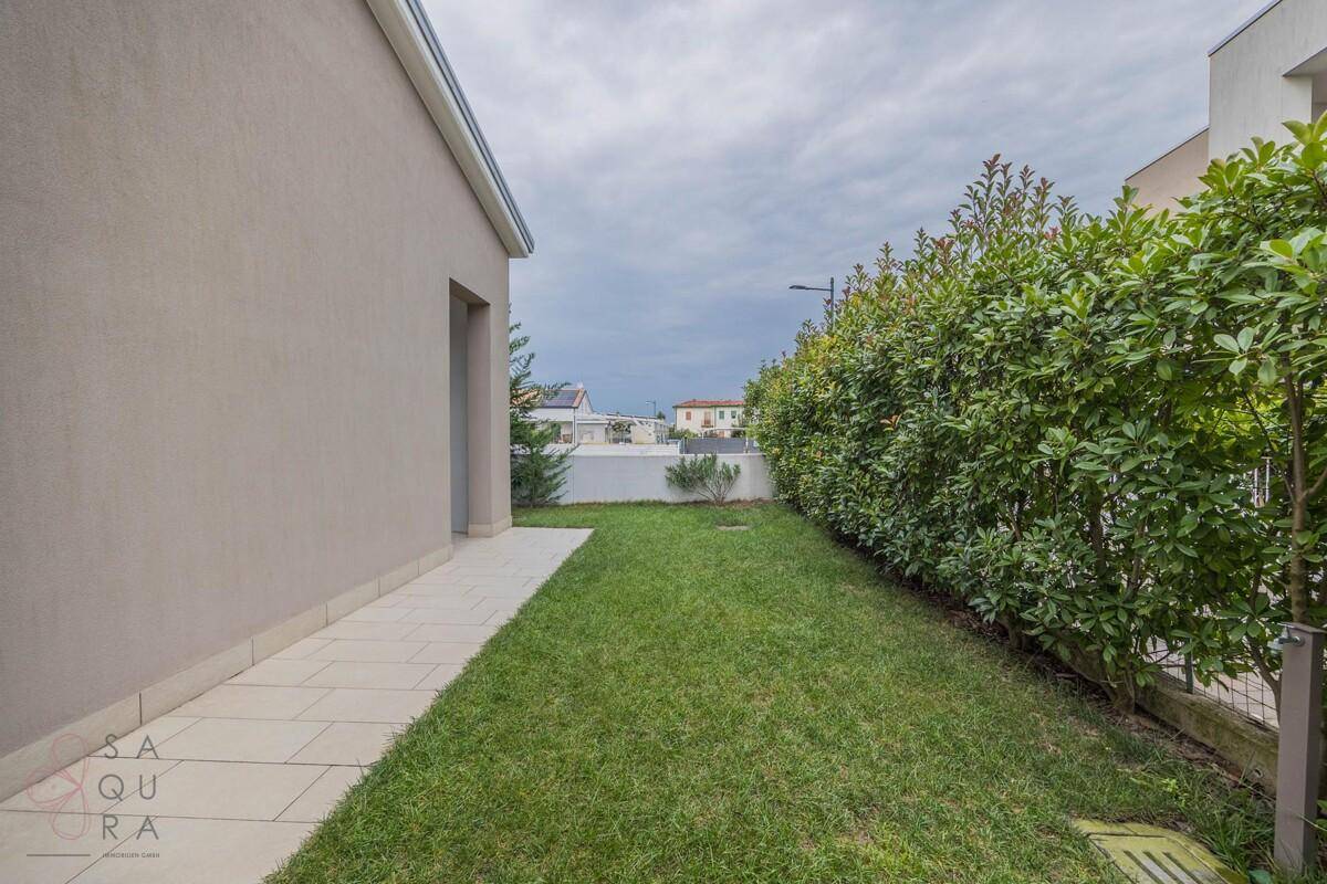 Langer Gartenstreifen mit grüner Hecke und gepflegtem Rasen neben dem Haus.