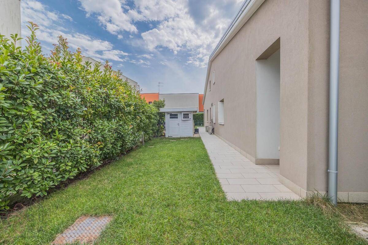 Gepflegter Gartenbereich mit Rasenfläche, Hecke und einem kleinen Gartenhaus.
