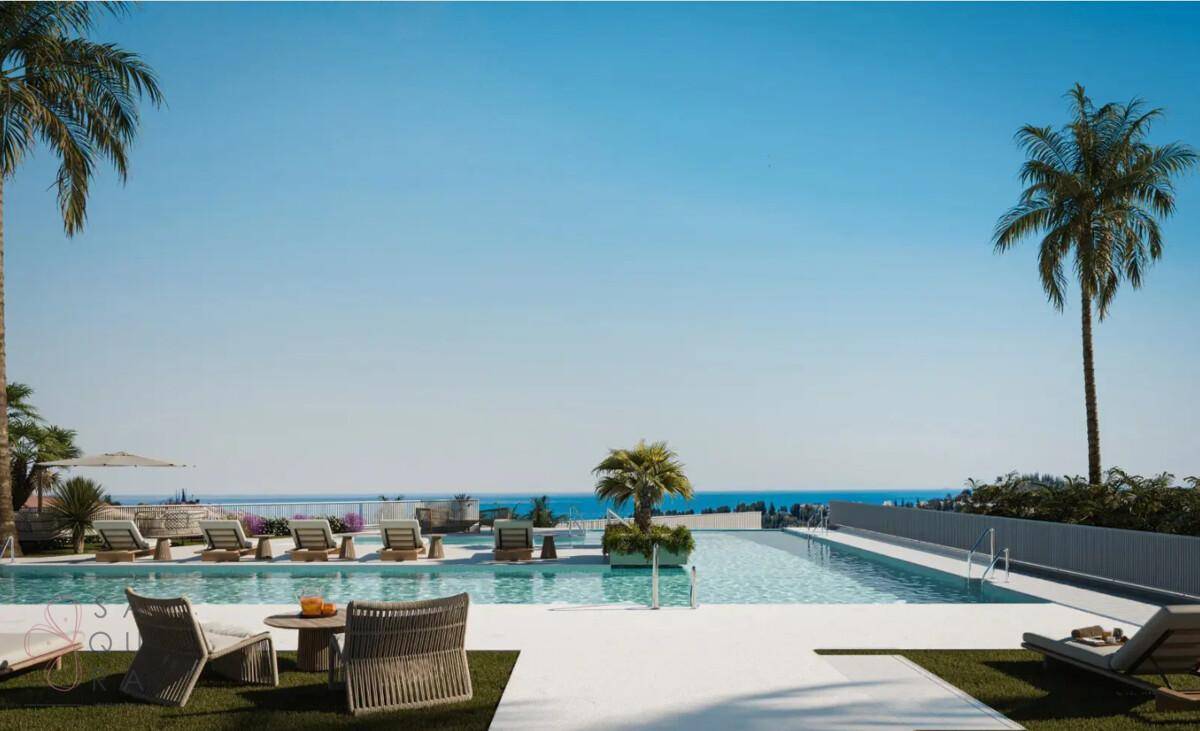 Weitläufiger Außenpoolbereich mit Liegestühlen, Palmen und Panoramablick auf das Meer.
