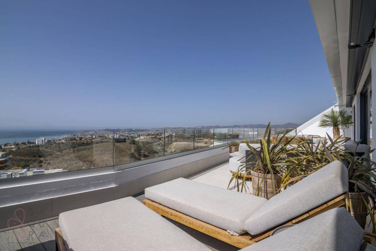 Sonniger Terrassenbereich mit Liegestühlen und weitem Blick auf die Küste und das Meer.