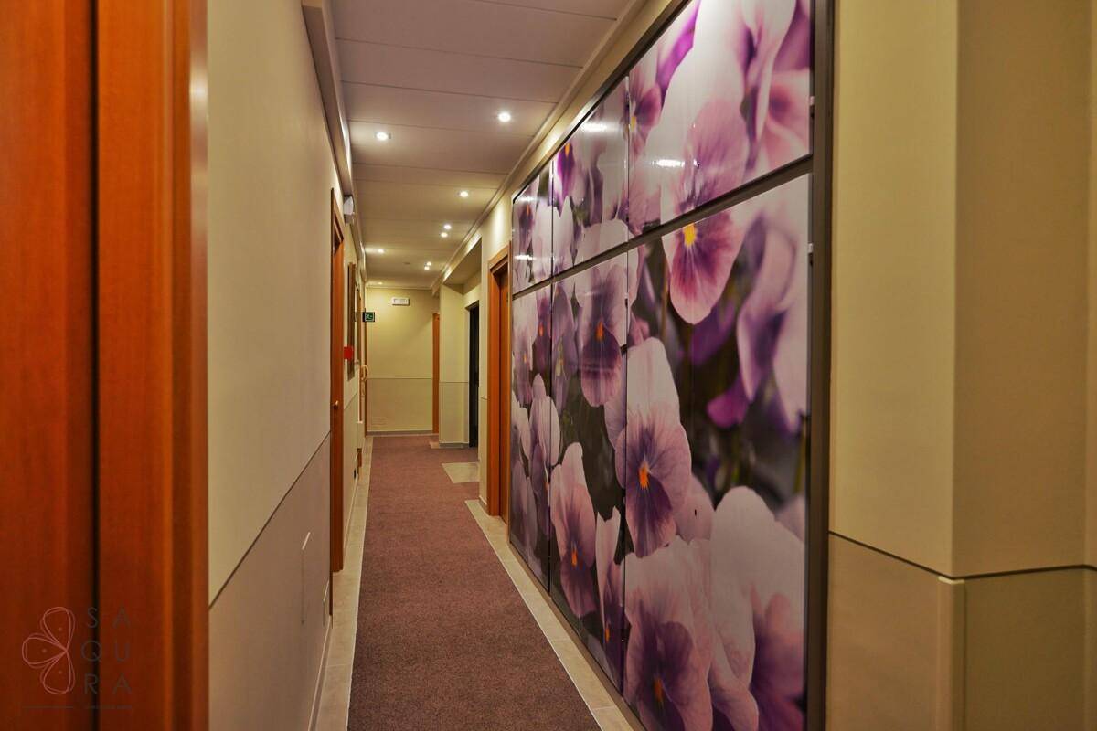 Langer Hotelflur mit Teppichboden und einer auffälligen Wanddekoration mit Blumenmotiv.