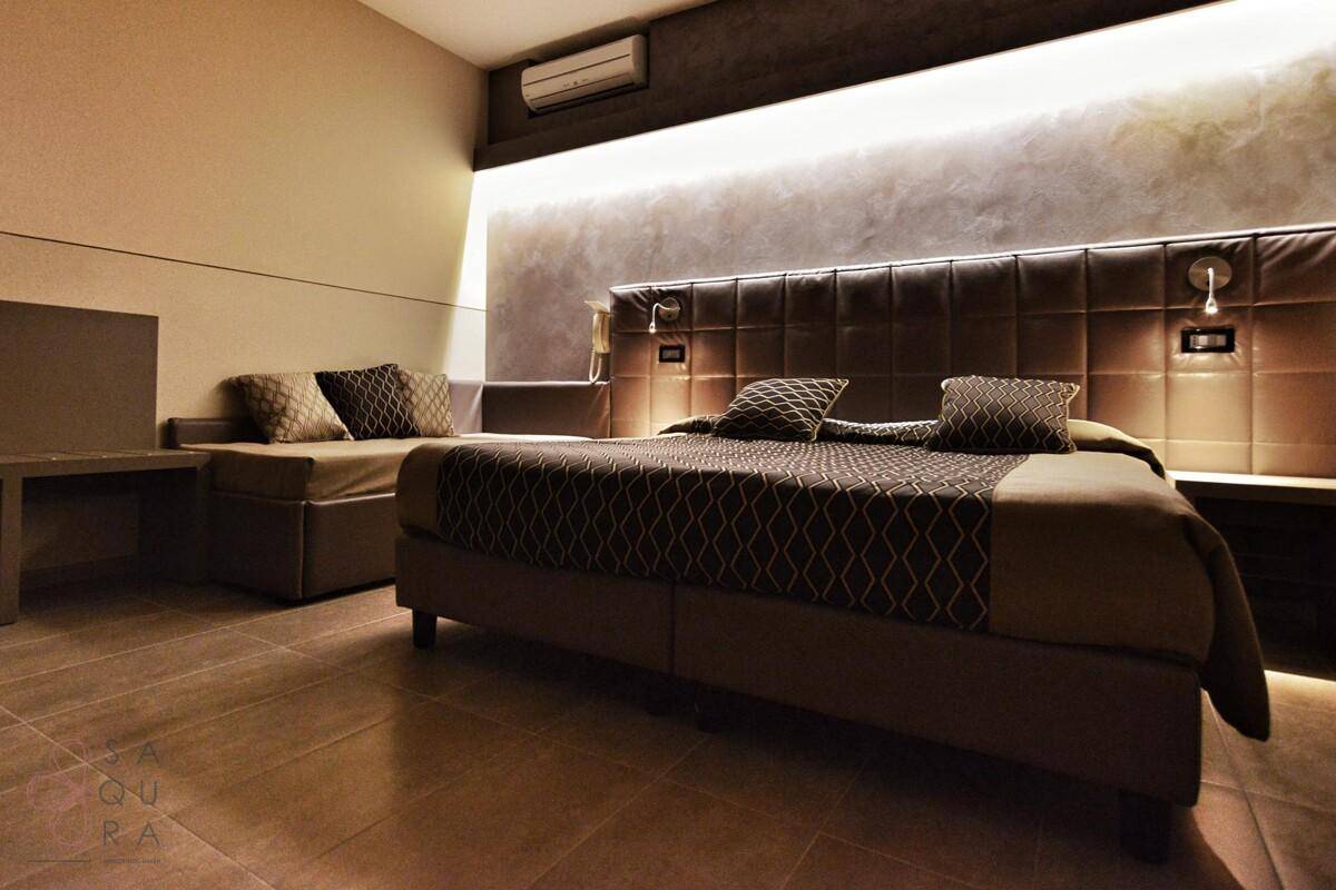 Elegantes Schlafzimmer mit einem großen Bett, gepolstertem Kopfteil und stimmungsvoller Beleuchtung.